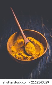 Indian turmeric powder, curcuma spice in small bowl with spoon, Haldi powder on wooden background