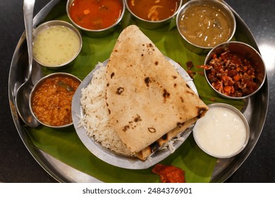 Indian vegetarian platter Thali meals. Having paneer butter masala dal makhani flat bread or naan and rice served in a steel plate and banana leaf Tamil Nadu, Bangalore Karnataka India. - Powered by Shutterstock