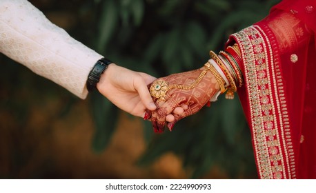 indian wedding candid photo of groom and bride holding hand