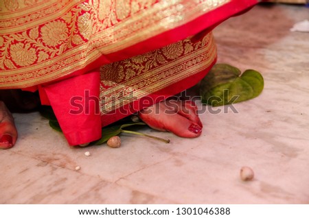 Indian wedding rituals. Bengali bride removing betel leaf and betel nuts by her feet using a stone.