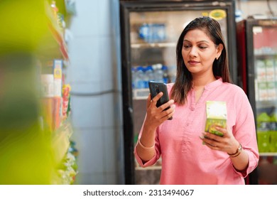 Indian woman checking product information in smartphone at supermarket - Powered by Shutterstock