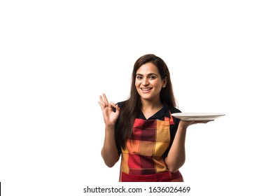 Indian Woman chef wearing apron and holding empty dinner plate with different  facial expressions, standing isolated over white background