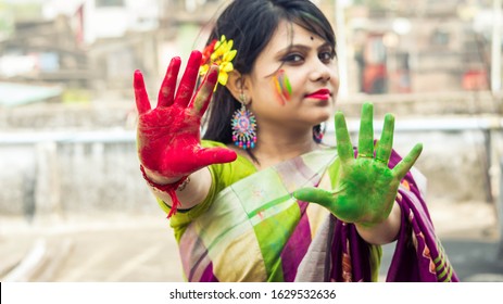 An Indian woman dressed in saree, celebrating Holi with colors on her hands and face - Holi concept (selective focus on hand) - Shutterstock ID 1629532636
