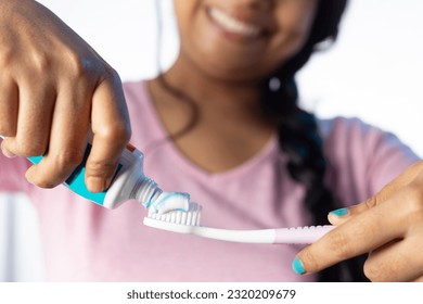An Indian woman female girl applying toothpaste on toothbrush on white background with smiling face - Shutterstock ID 2320209679