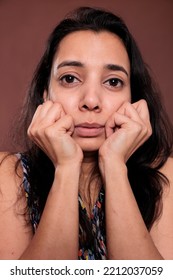 Indian Woman Holding Clenched Fists On Cheeks Closeup Portrait, Cute Pose. Calm Lady Touching Face With Hands Close View, Person With Neutral Facial Expression Looking At Camera