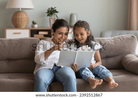 Indian woman and little girl enjoy fairytale, caring mother reading fascinating book her preschooler daughter spend weekend at home. Pastime and hobby, good life habit, children development concept
