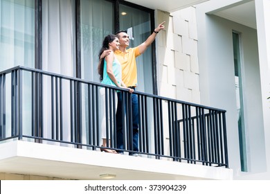 Indian woman and man standing on balcony of their new home