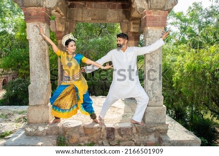 Indian woman Odissi dancer doing classical dance along with teacher or master outdoor. female do Orissi dance traning with coach. art and culture of india.