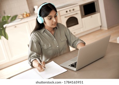 Indian Woman Student Wear Headphones Learning Online Watching Online Class Webinar Seminar Training Looking At Laptop Computer Elearning Remote Lesson Writing Notes, Video Conference Calling At Home.