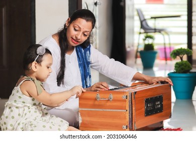 Indian Woman Teacher  Teaching  Harmonium To Cute Kid At Home. Mom Play Music And Singing To Her Daughter, Enjoy Spend Time Together, Mother And Child 