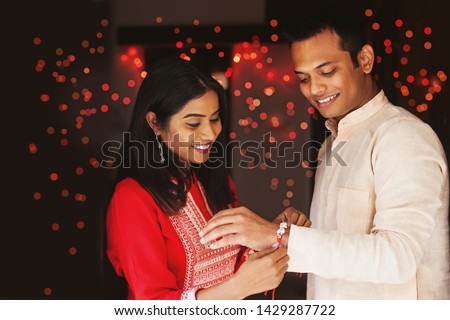 Indian woman tying rakhi on her brother's hand to celebrate Raksha Bandhan (Rakshabandhan) / Bhai dooj