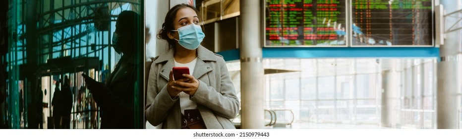 Indian Woman Wearing Face Mask Using Mobile Phone At Train Station Indoors