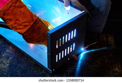 A Indian Woman Wearing A Pink Long Sleeve Jacket, Safety Welding Mask And Leather Gloves, Welding A Metal Case For Computer Server Rack, With Sparks