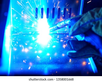 A Indian Woman Wearing A Pink Long Sleeve Jacket, Safety Welding Mask And Leather Gloves, Welding A Metal Case For Computer Server Rack, With Sparks