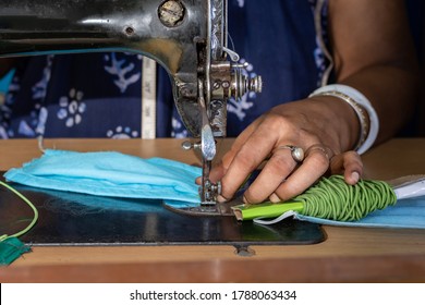 Indian Woman Working On Old Sewing Machine - Making Homemade Face Masks Against Coronavirus Or Covid19 Spreading, Closeup Detail On Moving Needle And Fingers Holding Fabric