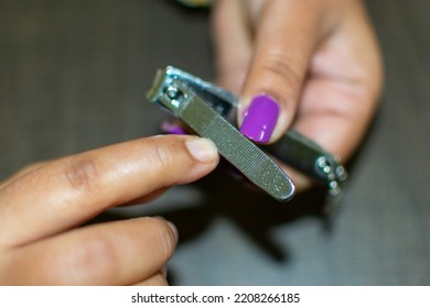 An Indian women cutting and rescaling her nail by a cutter. Copy space image.Personal grooming. Selective focus.