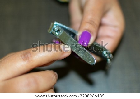 An Indian women cutting and rescaling her nail by a cutter. Copy space image.Personal grooming. Selective focus.