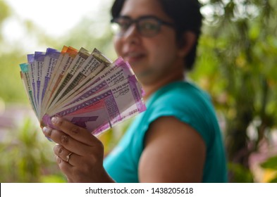 Indian Women Holding All The Colorful New Released Indian Rupees Currency Notes After Demonetisation In Denominations 10,50,100, 200, 500, Pink 2000 In Her Hands With Her Blur Face In The Background