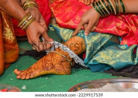 Indian Women putting anklets bridal foot, Indian bride getting her payals. Indian bride being helped by putting her anklets