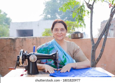 Indian women stitching cloths by machine at out side the home 