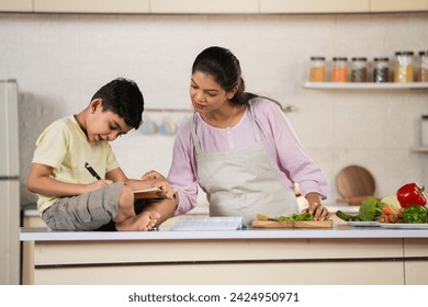 Indian working mother at kitchen helping her kid or child to do homework - concept of multitasking, parenthood and family responsibility - Powered by Shutterstock