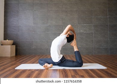 Indian yogi doing king pigeon yoga pose in gym. Man practicing advanced yoga. Yogi concept. Side view. - Powered by Shutterstock