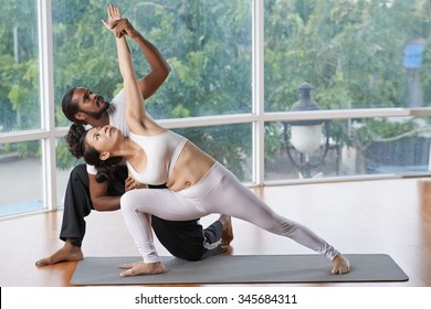 Indian Yogi Helping Woman To Perform Triangle Position