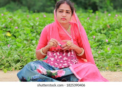 An Indian Young Attractive Stylish Blonde Fashion Female Make- Up Artist Sitting In The Garden, Closing The Nail Polish Decay And Thinking About The Solution To The Business Problems Ahead Of Her