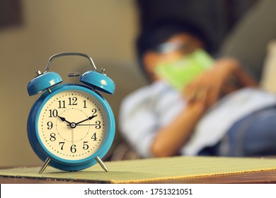 Indian Young Boy Sleeping With Textbook And Alarm Is In Front Of Him