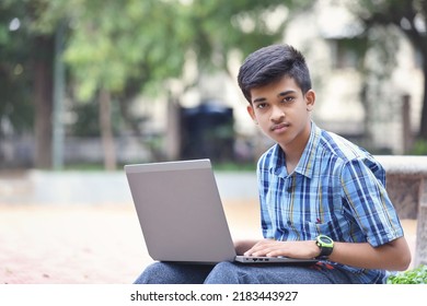 Indian Young Boy Using Laptop While Sitting Outside Park	
