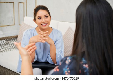 Indian Young Businesswoman Sitting On Sofa And Listening To Her Colleague With Smile During Business Interview At Office