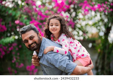 Indian young father carrying his small daughter in the park - Powered by Shutterstock