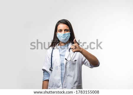 Indian young female doctor with uniform and mask showing success of thumbsup