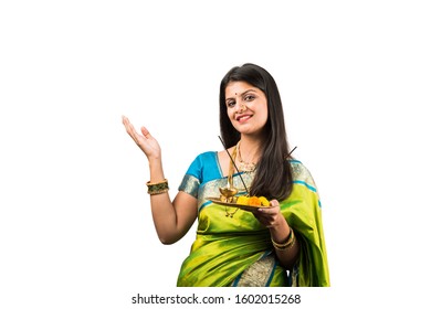 Indian young female in saree holding Pooja Thali standing isolated against white background, celebrating Diwali or hindu festival. selective focus