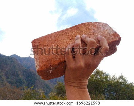 Indian young guy waved his hand with a brick. Popular protests and attack with stones.