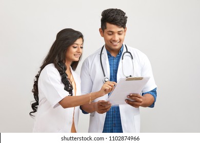 Indian Young Male And Female Doctor Examining Patient Papers 