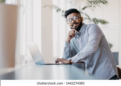Indian young man with laptop standing in modern office - Shutterstock ID 1442274383