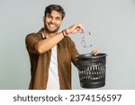 Indian young man taking off throwing out glasses into bin after medical vision laser treatment therapy surgery looking smiling at camera, heal, cure. Arabian guy isolated on studio gray background