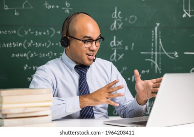 Indian young teacher man sitting wearing headset teaching online video conference live stream by laptop. Asian teacher teaching mathematics class webinar online for students learning. - Powered by Shutterstock