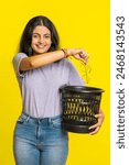 Indian young woman taking off throwing out glasses into bin after medical vision laser treatment therapy surgery looking smiling at camera heal cure. Arabian girl on studio yellow background. Vertical