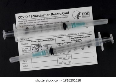 Indianapolis - Circa February 2021: COVID-19 Vaccination Record Card with syringes or hypodermic needles. Vaccination Record Cards will be offered with each shot and a reminder for the second dose.