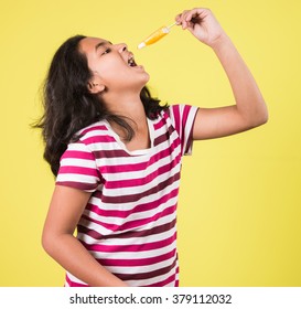 Indian/Asian Cute Little Girl Eating Ice Cream In Cone Or Mango Bar/candy. Isolated Over Colourful Background