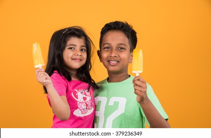 Indian/Asian Cute Little Kids Eating Ice Cream/mango Bar Or Candy. Isolated Over Colourful Background