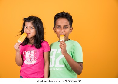 Indian/Asian Cute Little Kids Eating Ice Cream/mango Bar Or Candy. Isolated Over Colourful Background