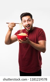 Indian/asian Man Eating Hot Noodles Or Ramen In A Red Bowl With Chopsticks