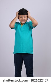 Indian/asian School Kid Or Boy Pulling Hair In Sadness Or Distress Because Of Study Pressure Or Competition, Standing Isolated Over White Chalkboard Background