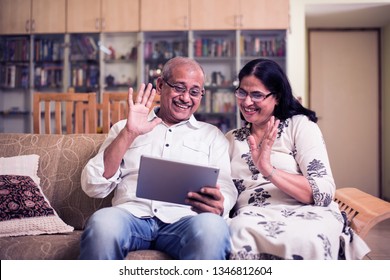 Indian/asian Senior Couple Video Chatting On Tablet/computer While Sitting At Couch Or In Garden At Home, Selective Focus
