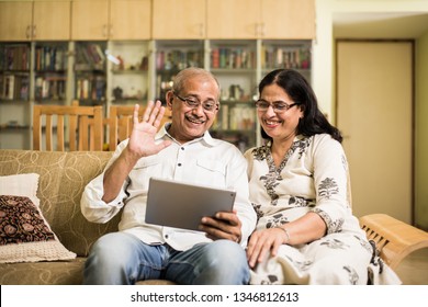 Indian/asian Senior couple video chatting on tablet/computer while sitting at couch or in garden at home, selective focus
 - Powered by Shutterstock