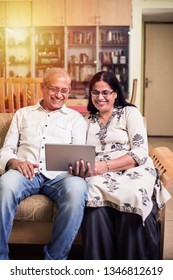 Indian/asian Senior Couple Video Chatting On Tablet/computer While Sitting At Couch Or In Garden At Home, Selective Focus
