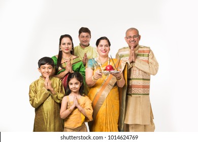 Indian/Asian smart family welcoming Lord Ganesha Idol on Ganesh Festival with Pooja Thali and sweets. standing isolated over white background